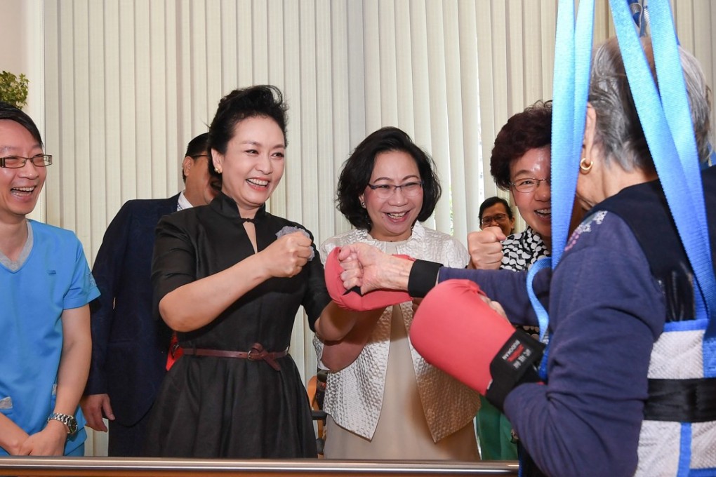 First lady Peng Liyuan (in black) trades fake punches with an elderly resident. Photo: ISD
