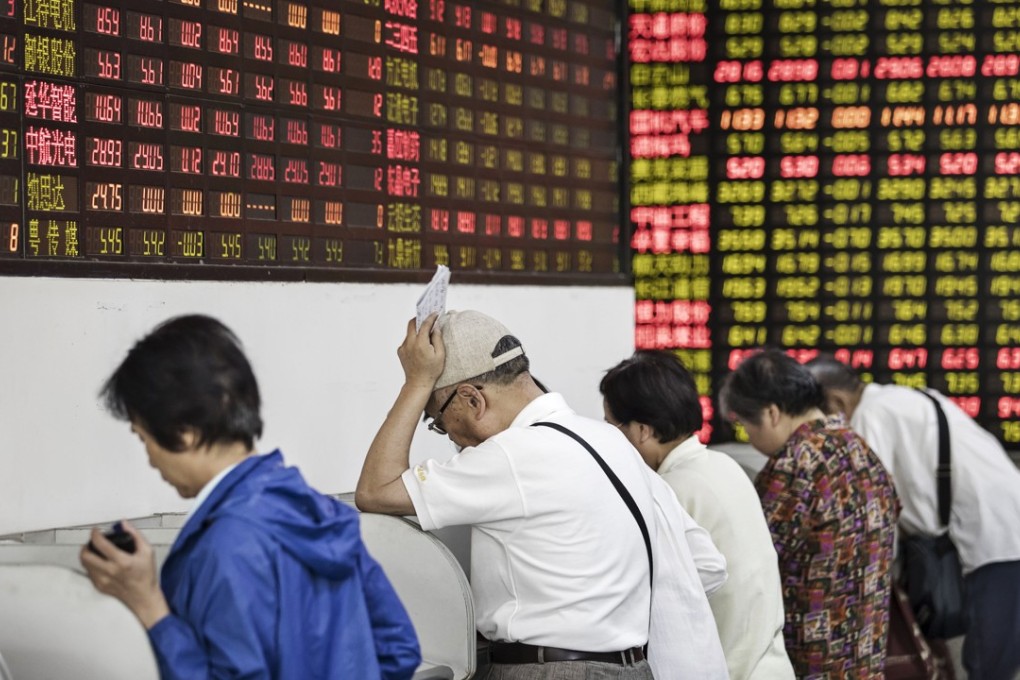 Investors stand at trading terminals in front of electronic stock boards at a securities brokerage in Shanghai. Photo: Bloomberg.