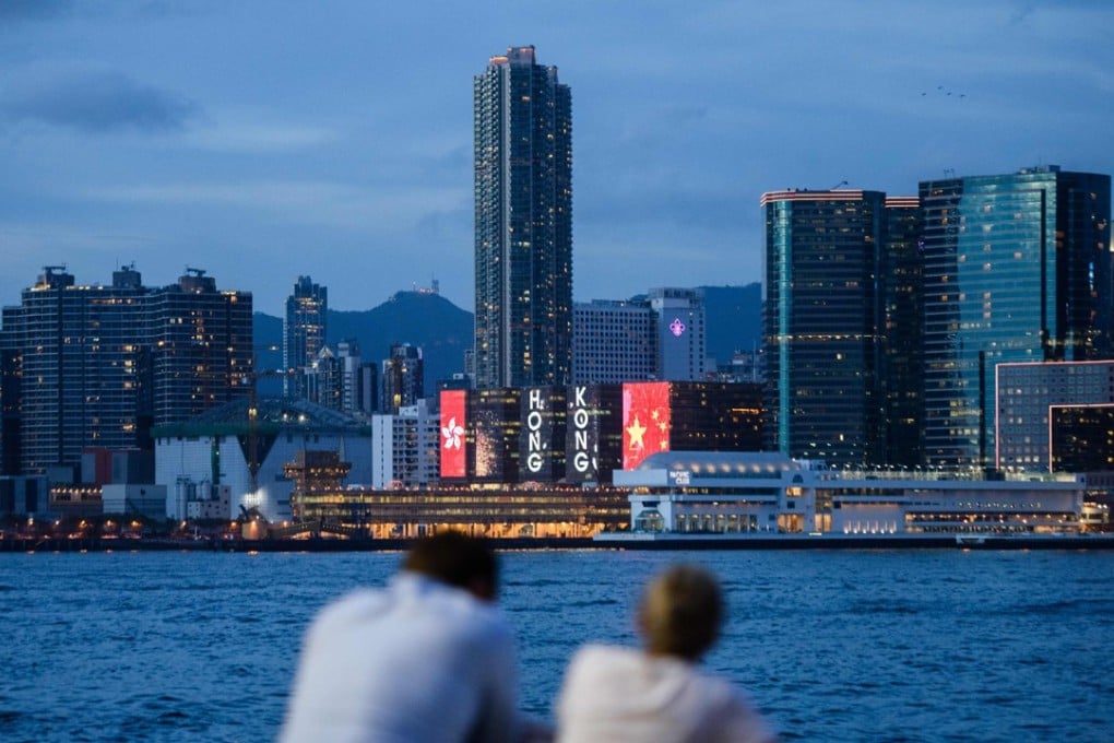 Two friends chat in front of a view of Victoria Harbour and a light display commemorating the 20th anniversary of the city's handover from British to Chinese rule in Hong Kong, ahead of the handover anniversary on July 1. Photo: AFP