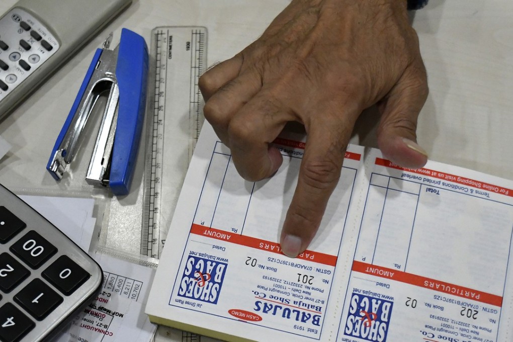 An employee displays a receipt book showing a store's goods and services tax identification number (GSTIN). Photo: Bloomberg