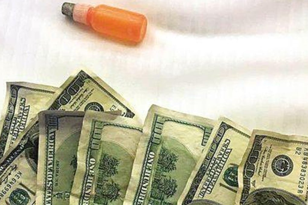 Some real US$100 banknotes with a vial of the ‘special chemical agent’ to remove dye. Photo: Handout