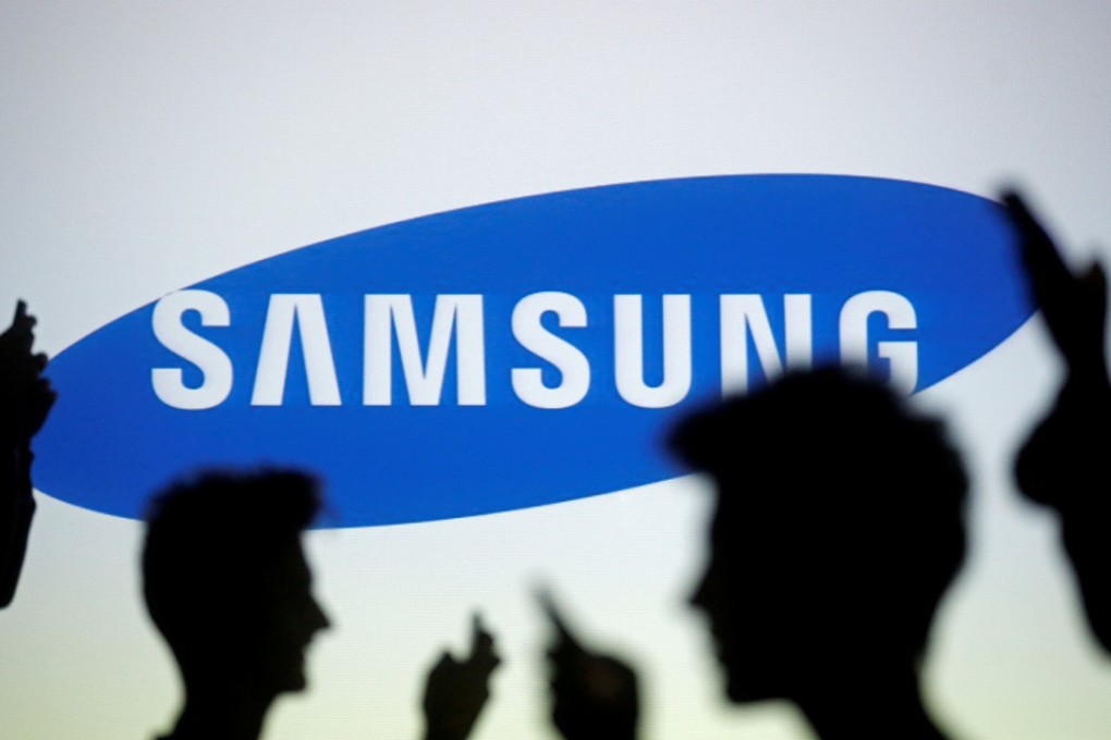 People are silhouetted as they pose with mobile devices in front of a screen projected with a Samsung logo. Photo: REUTERS/Dado Ruvic