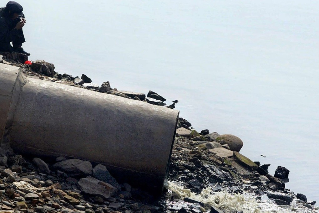 A man sits by the banks of the Yellow River beside a pipe emitting raw sewage in Lanzhou, Gansu province, in this 2003 file photo. Photo: AFP