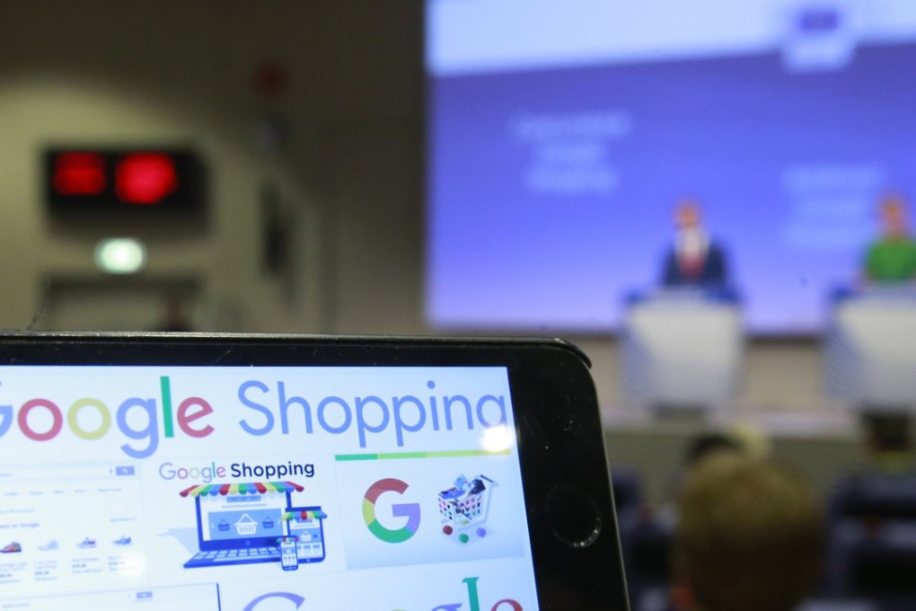 Google Shopping logos on a phone as European Commissioner for Competition Margrethe Vestager (R) speaks during a press conference on an Antitrust case against Google Shopping in Brussels, Belgium on 27 June 2017. Photo: EPA
