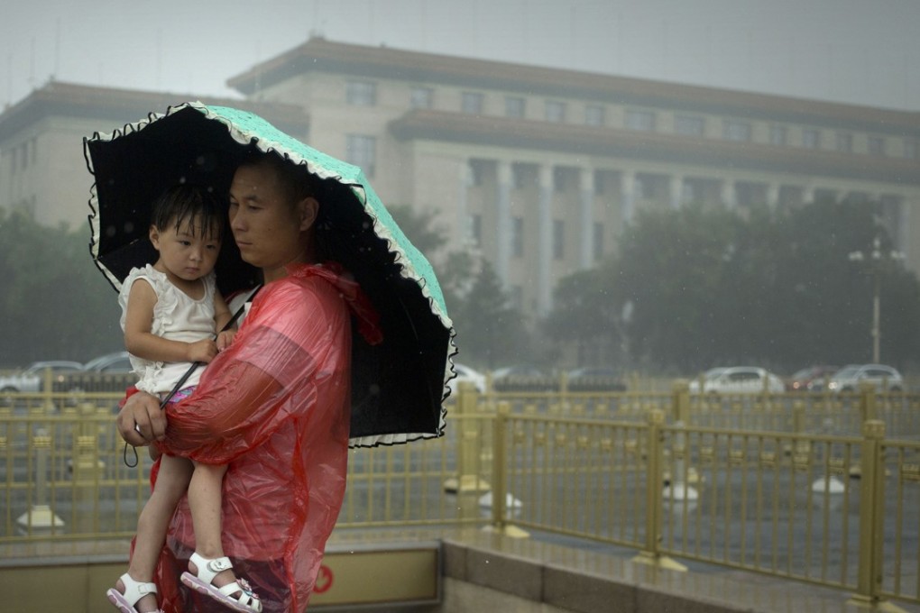 A man shelters a girl under an umbrella near the Great Hall of the People in Beijing on Thursday. Photo: AP