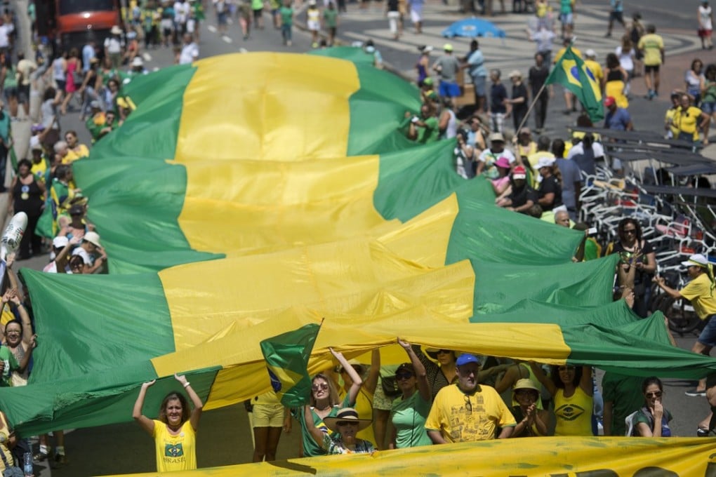 People carry a flag with the national colours of Brazil to protest against corruption on Copacabana beach. Photo: AP
