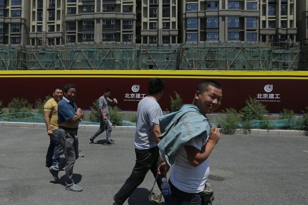 Migrant workers walk past a construction site in Beijing last month. Many Chinese who left their rural hometowns in search of jobs in the country’s booming coastal cities are now in need of new work as construction projects stall and trade volume decreases. Photo: EPA