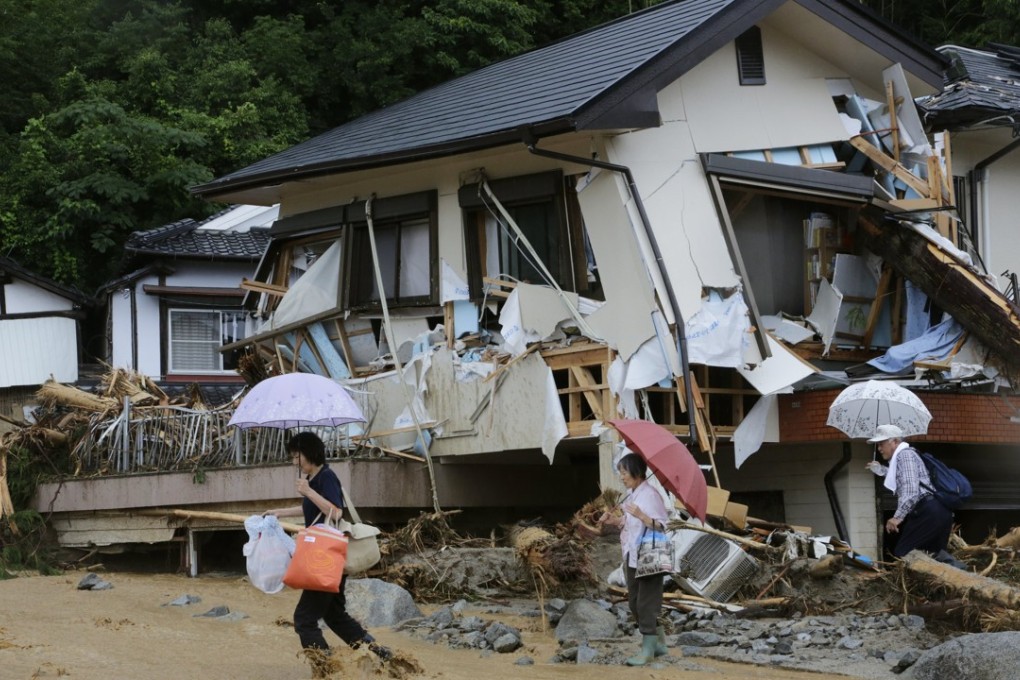 Residents cross a flooded stream overing a road at a landslide-devastated area as they evacuate from a makeshift evacuation centre in Asakura. Photo: EPA
