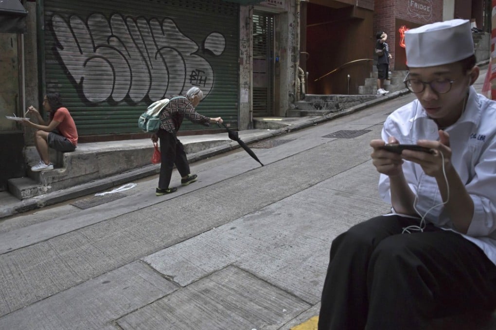A restaurant worker takes a break in Central, Hong Kong. In many advanced societies, the job imbalance is skewed – the existing labour force fears retrenchment, whereas the young face intense competition for scarce jobs. Photo: AP