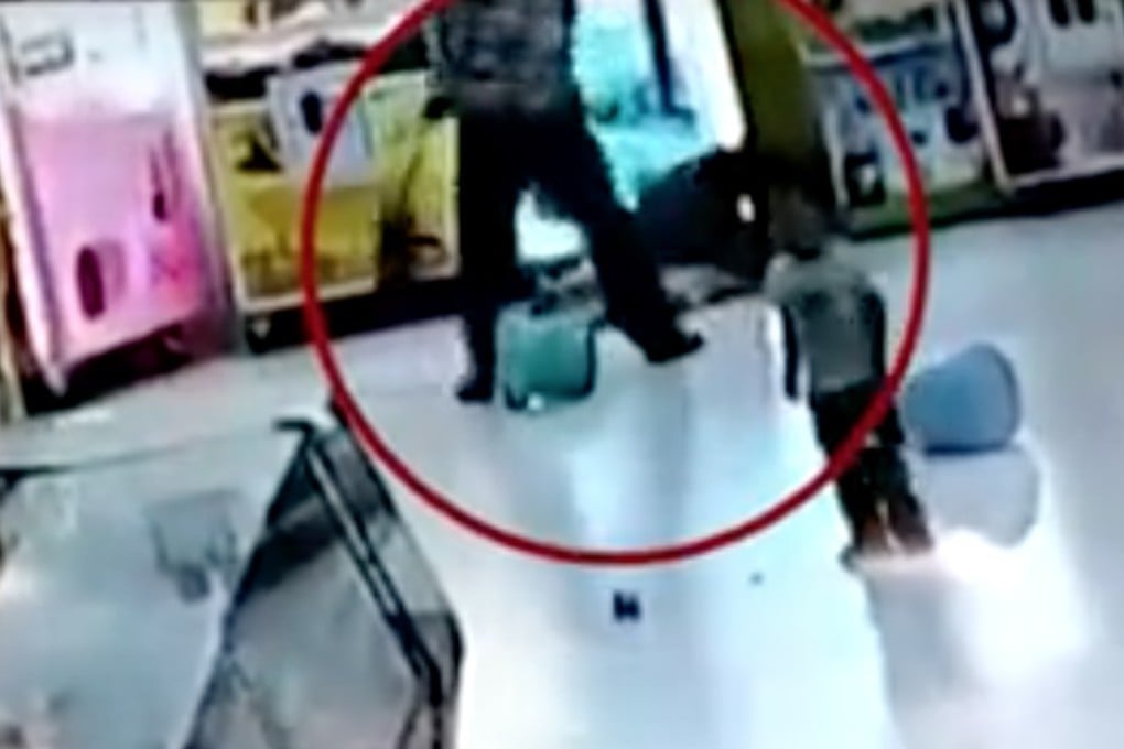 In this still from the video, the father can be seen hitting his daughter with a broom as she lies on the floor. Her little brother stands in the foreground. Photo: Handout