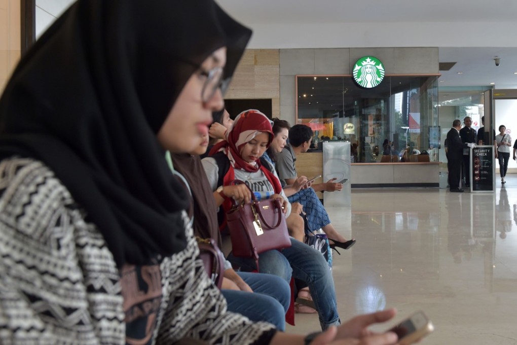 Indonesian Muslim women sit outside a Starbucks cafe at a shopping mall in Jakarta. Muslims in Indonesia were urged to boycott Starbucks by major Islamic groups accusing the coffee chain of being pro-gay rights. Photo: AFP