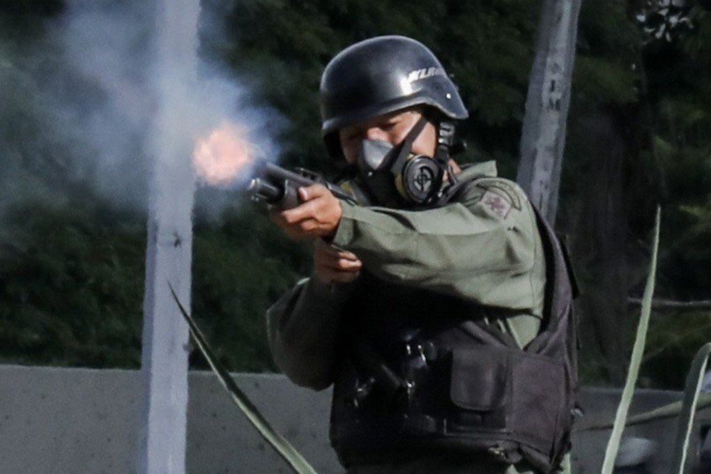 A member of the Bolivarian National Guard fires during a demonstration against the constituent process in Caracas. Photo: EPA