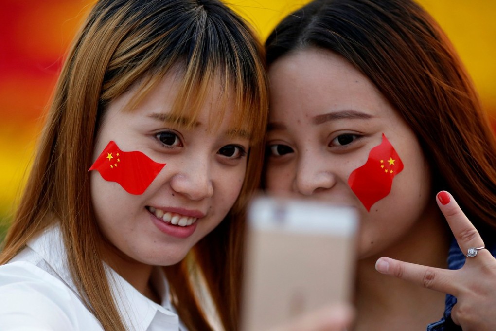 Girls wearing Chinese flags on their cheeks take selfies in Beijing. Sales of high-resolution smartphone camera lenses have been growing rapidly because of the popularity of dual-camera models and more powerful front cameras for taking selfies. Photo: Reuters