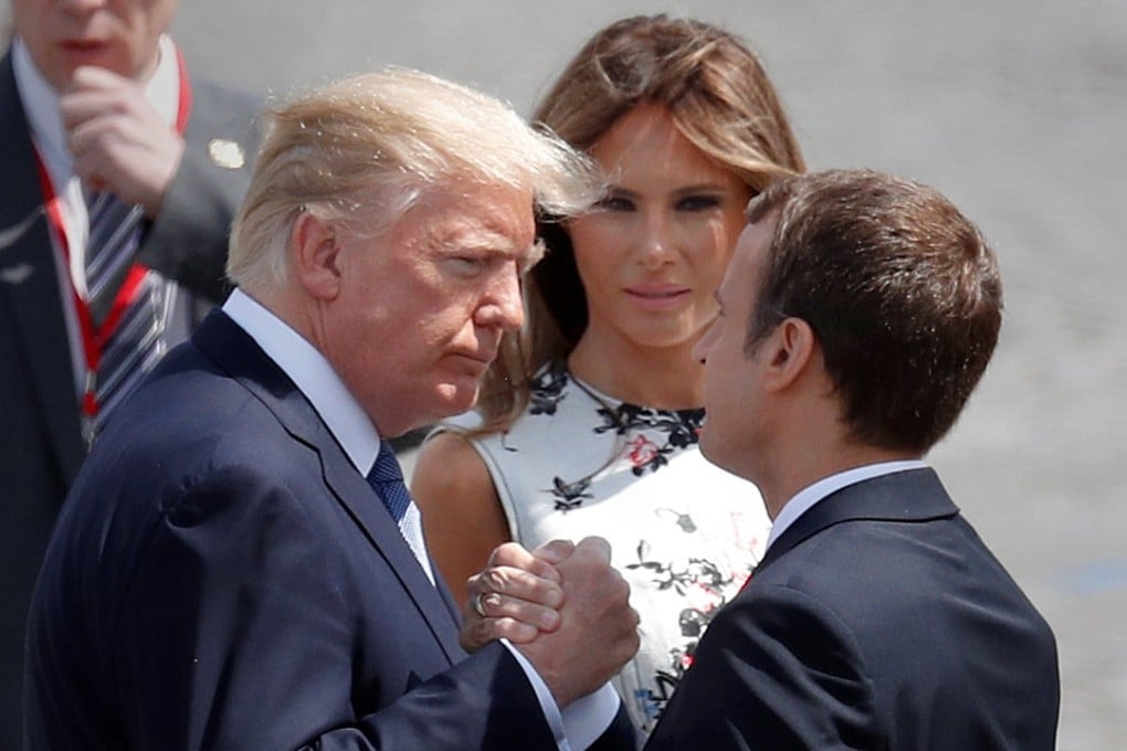 French President Emmanuel Macron shakes hands with US President Donald Trump as First Lady Melania Trump looks on after the Bastille Day parade. Photo: Reuters