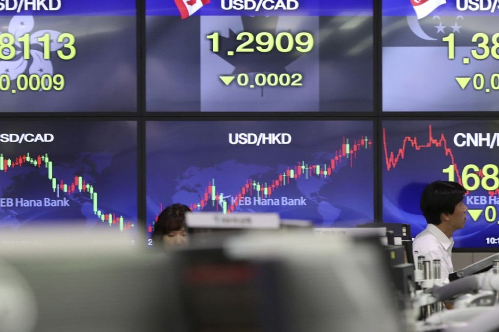 A currency trader walks by screens showing the foreign exchange rates at the foreign exchange dealing room in Seoul, South Korea. The dollar tumbled to a 10-month low on rising bets the Fed will not raise rates again in 2017. Photo: AP