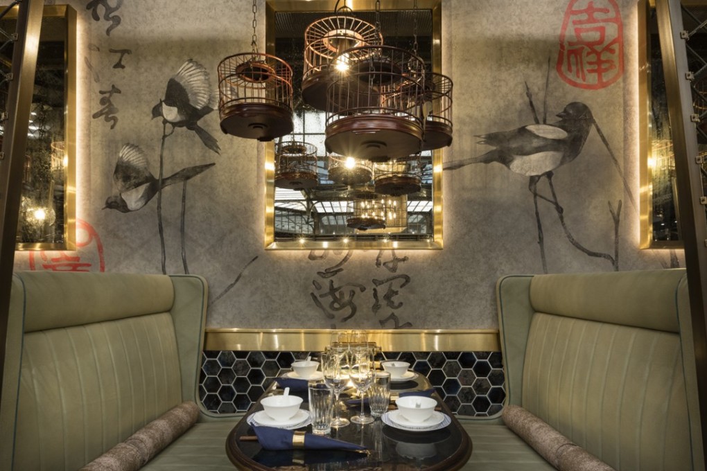 Booth seating in Mott 32 in Vancouver, with bird cages housing light bulbs and hand-painted walls.