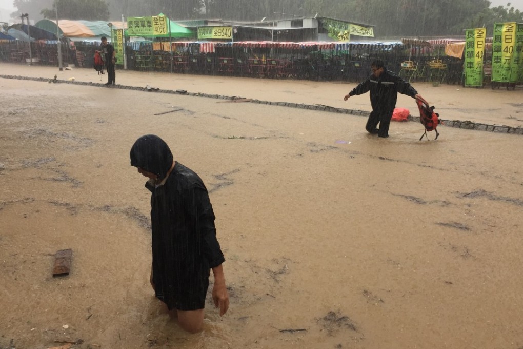 Pedestrians struggle to cross flooded areas in Tai Mei Tuk, Tai Po. Photo: Denise Tsang