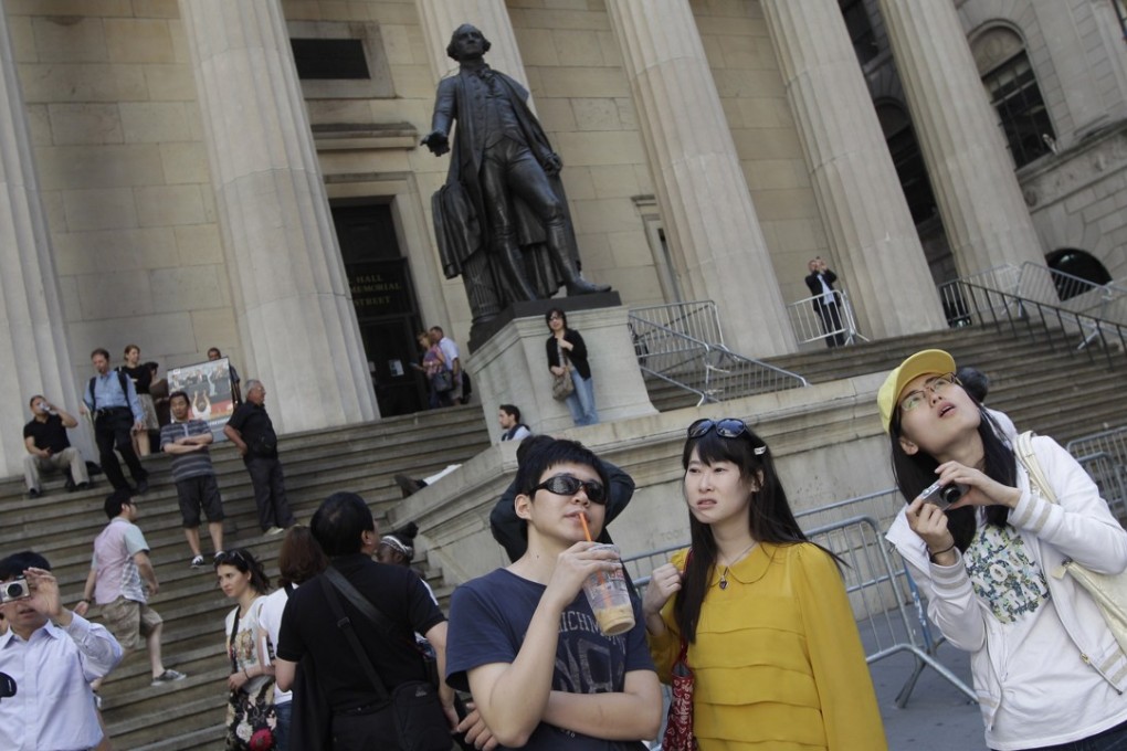 Chinese tourists take in the sights of the New York Stock Exchange and Federal Hall National Memorial. Photo: AP