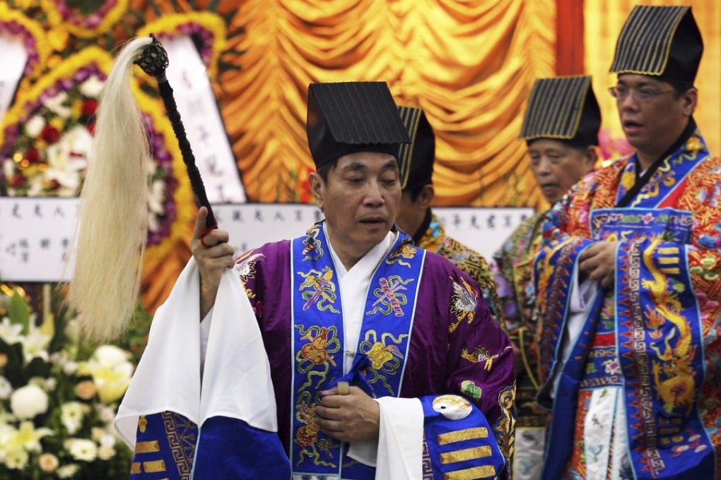 A Taoist head priest performs a number of critical roles at a funeral, including warding off evil spirits with a peach wood sword and breaking nine tiles which symbolise the levels of hell. Photo: Martin Chan