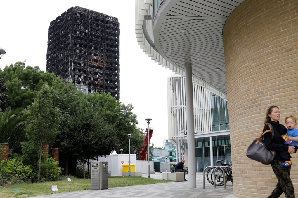 A woman carries a child near the shell of London’s Grenfell Tower, charred by fire. Photo: Reuters