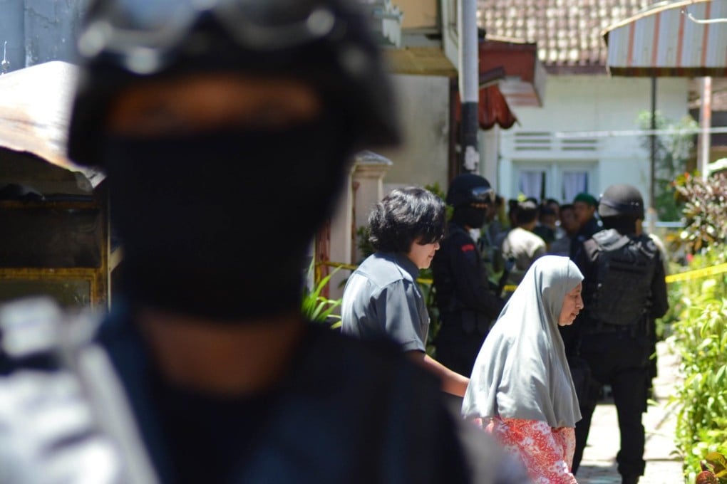 Civilian women walk as Densus 88 counterterrorism police commandos conducting operations on a house in Malang located in eastern Java island. Photo: AFP