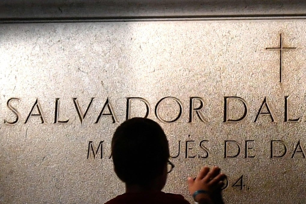 A child touches Salvador Dali's tombstone. Photo: AFP