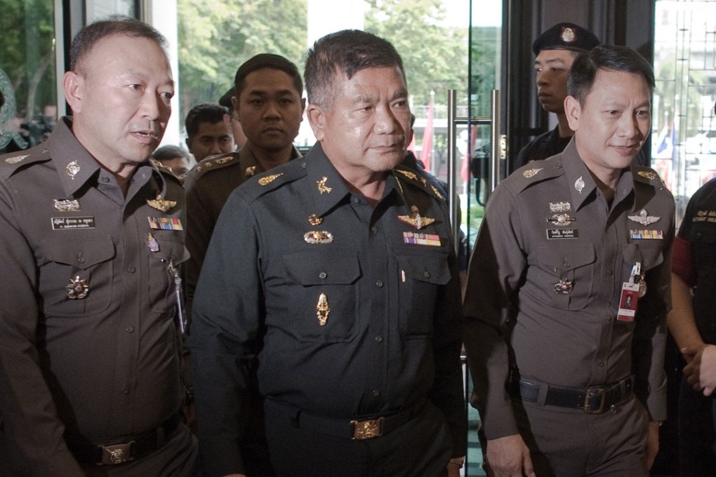 Thai Army Lieutenant General Manas Kongpan surrounded by police when he turned himself in. Photo: AFP