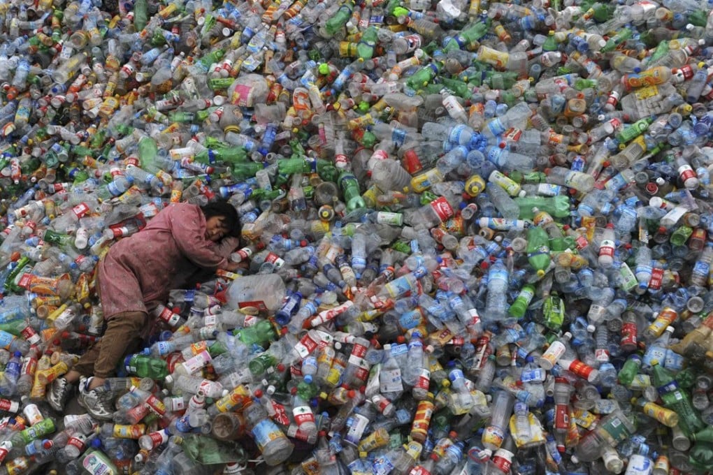 A labourer rests on piles of plastic bottles at a recycling centre in Zhejiang province. Photo: Reuters