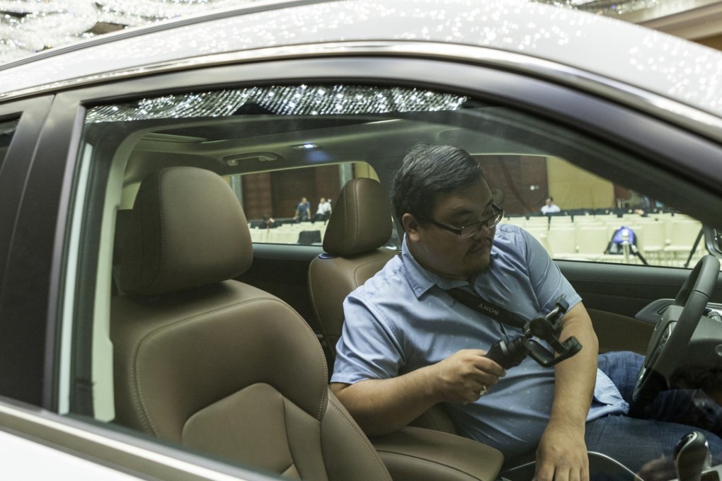 A member of the media takes a photograph inside a Zhejiang Geely Holding Group’s Boyue sport-utility vehicle (SUV) following a signing ceremony between DRB-Hicom and Geely in Kuala Lumpur, Malaysia. The deal may allow Proton to manufacture its first SUV. Photo: Bloomberg