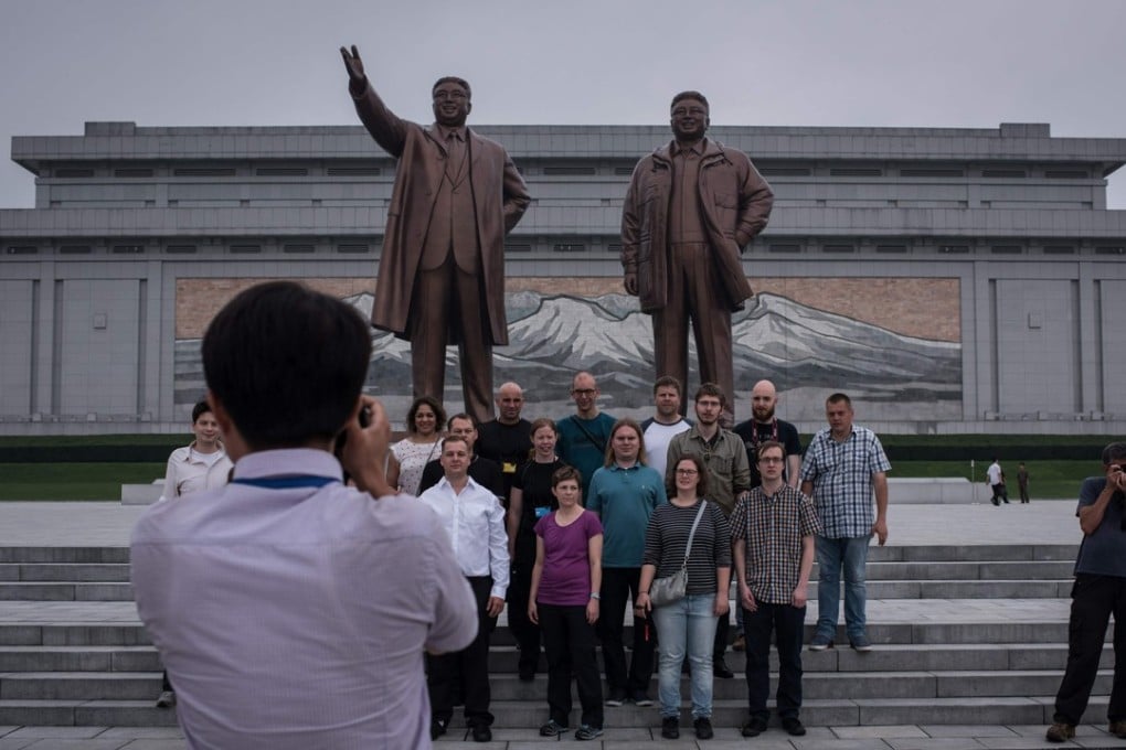Tourists pose for a group photo before statues of late North Korean leaders Kim Il-sung and Kim Jong-il. Photo: AFP