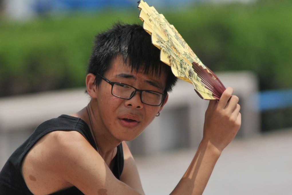 A boy shelters under a fan in Qingdao, eastern China’s Shandong province, as the mercury continues to soar across the country. Photo: AFP