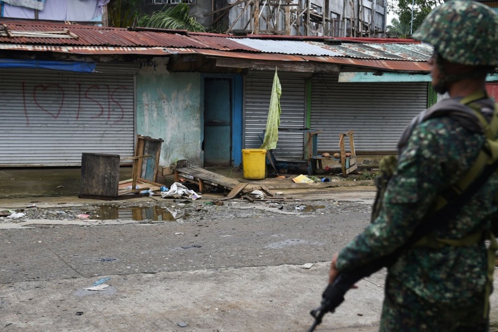 A Philippine soldier standing in front of a graffiti in a deserted neighbourhood in Marawi. Photo: AFP