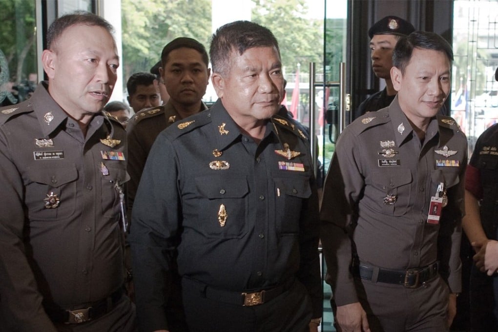 Thai Army Lieutenant General Manas Kongpan (centre) surrounded by police when he turned himself in. Photo: AFP
