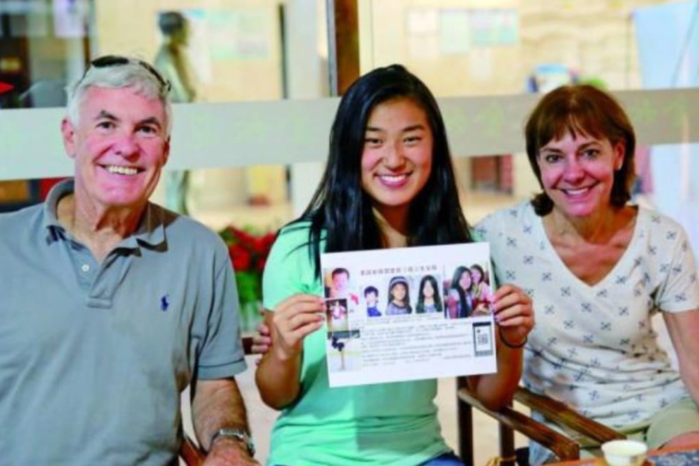 The girl, identified only as Lily and pictured with her parents, holds a leaflet appealing for information about her original family. Photo: Handout