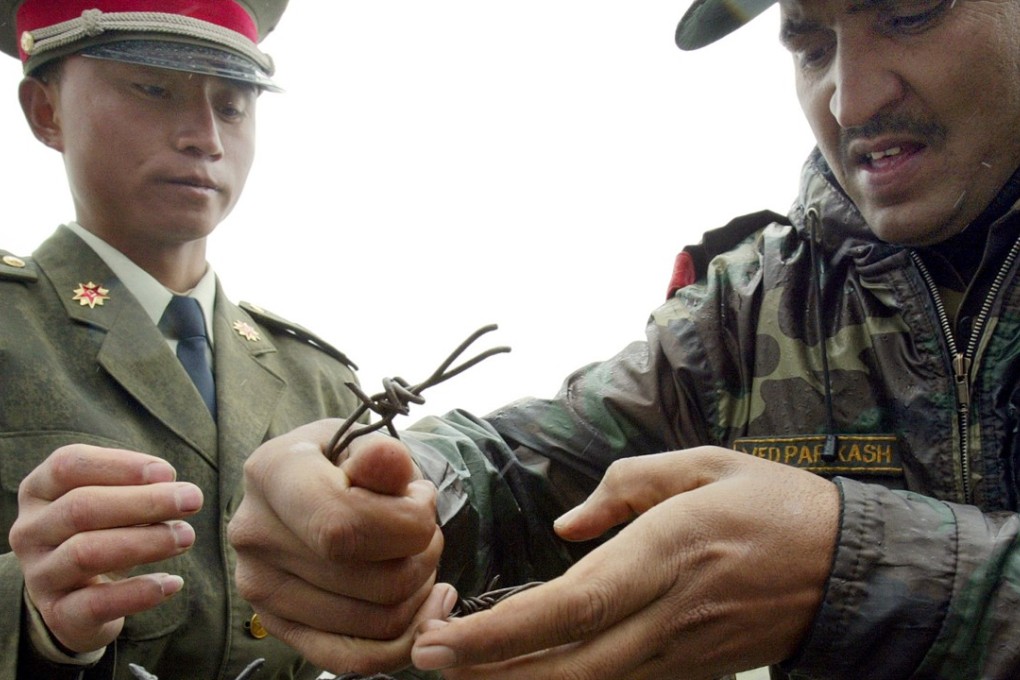 A Chinese and an Indian soldier mend a barbed-wire fence at the Nathu La border crossing between India and China in India's northeastern Sikkim state. Photo: AFP