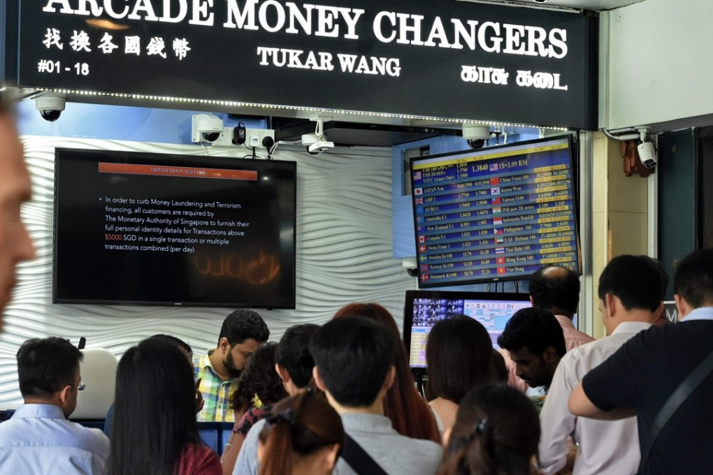 People queue in front of the money changer at the financial district in Singapore. The IMF said the US dollar remains overvalued by 10 to 20 per cent. Photo: AFP