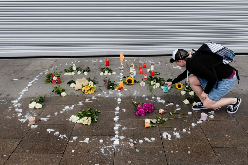 A woman places a candle at a makeshift memorial of flowers and candles arranged like a peace sign in Hamburg, northern Germany, at the site where a man killed one person and wounded several others in a knife attack the day before. Photo: AFP