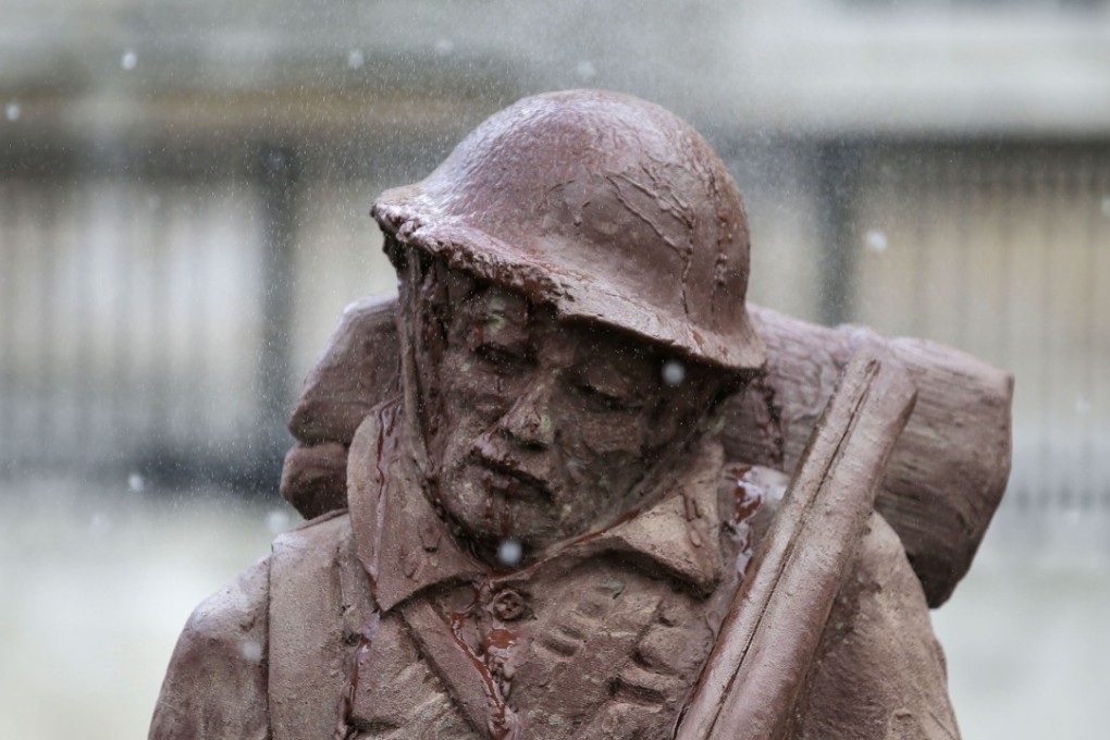 Artificial rain falls on the 'Mud Soldier' statue, which is sculpted from sand and mud from Passchendaele, during the unveiling ceremony on the North Terrace of Trafalgar Square in central London. Photo: AFP