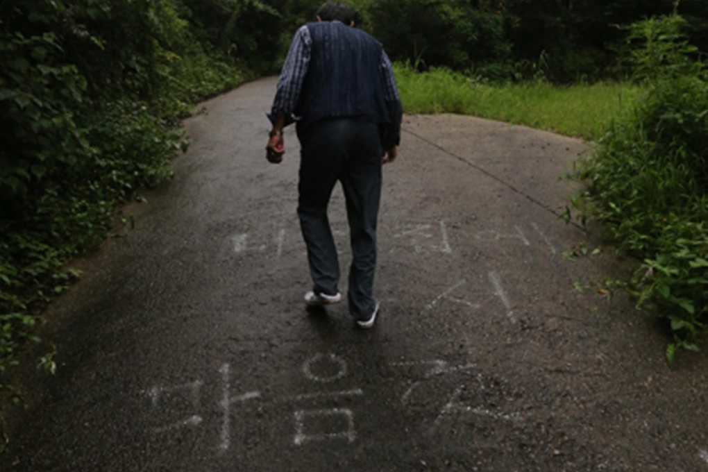 A villager walks on a path near the nude mansion. "Take off your clothes freely in your own home," reads the writing on the road. Photo: Yonhap