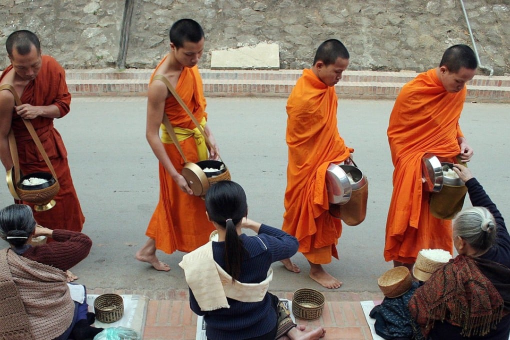 Women sitting along a street giving food to begging monks early in the morning in the town of Luang Prabang. Photo: AFP