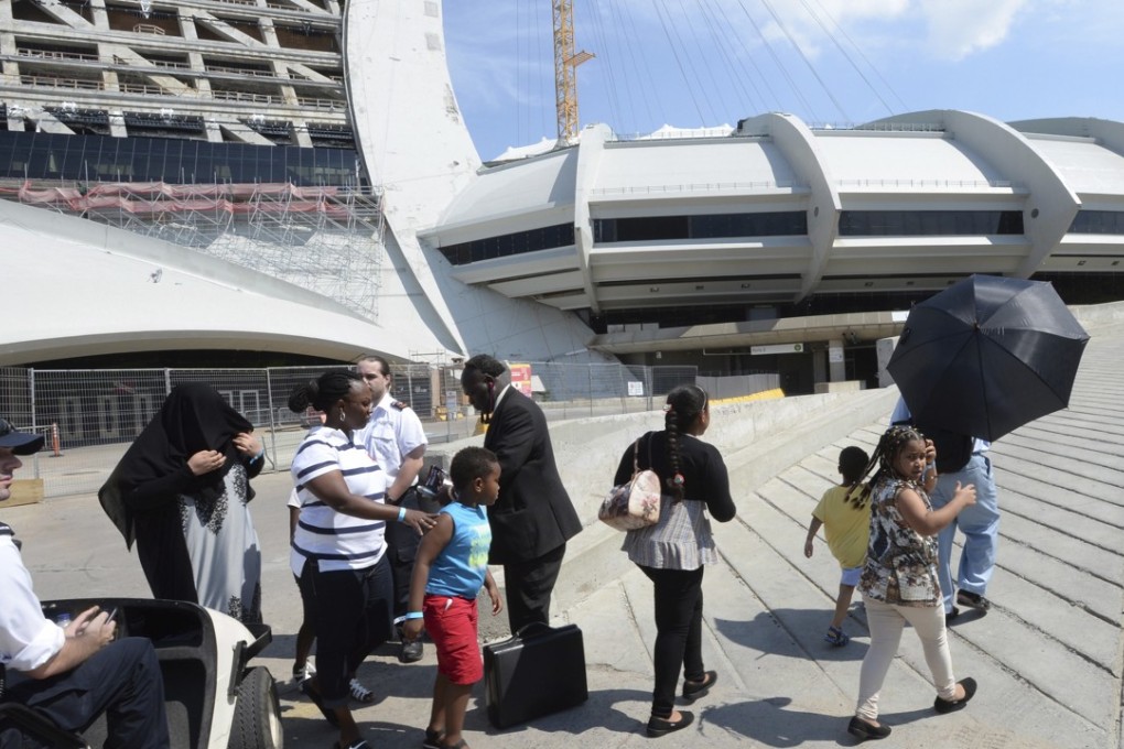 Asylum seekers take a walk outside Montreal’s Olympic Stadium on Wednesday. The stadium will be housing the asylum seekers after a spike in the number of people crossing at the United States border in recent months. Photo: AP