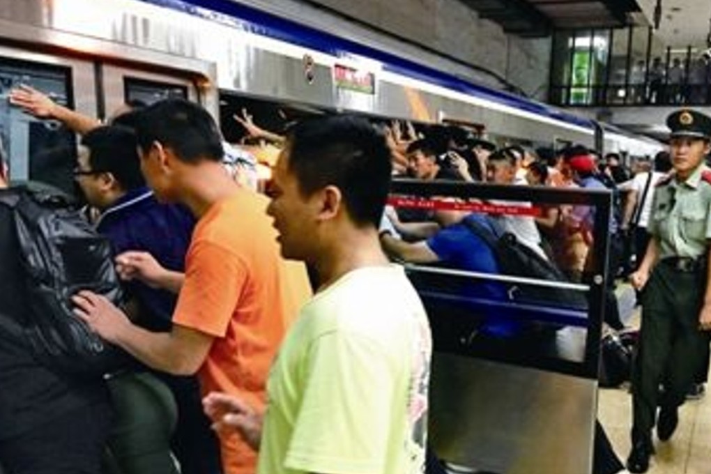 Commuters in Beijing push against the train in an effort to free a man who got stuck between the carriage and the safety barrier. Photo: Handout