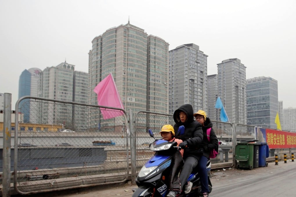 A man rides an electric bike, carrying children near apartment blocks in Beijing. Photo: Reuters