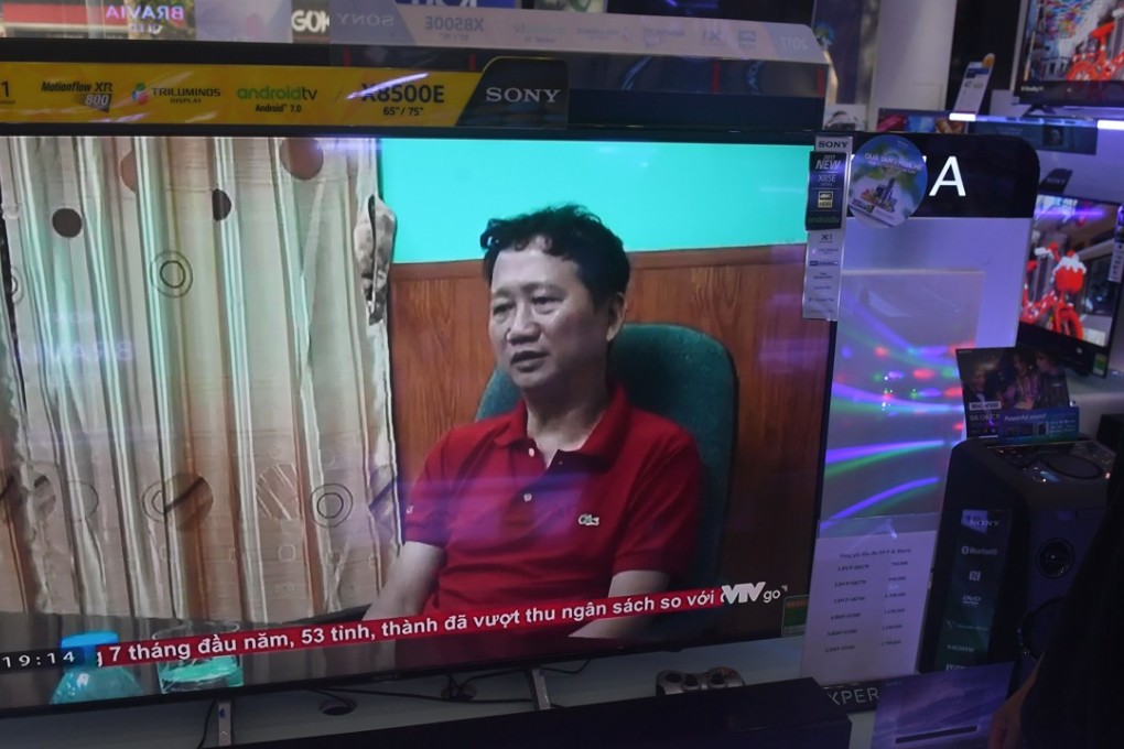 A store employee (R) watches a screen showing Trinh Xuan Thanh speaking in a clip aired by Vietnam's state television VTV, in Hanoi on August 4, 2017. Portrayed by the Vietnamese government as a Lexus-driving tycoon who flaunted his wealth while costing the state millions of dollars, Trinh Xuan Thanh fled the country as he fell under the cross hairs of a corruption crusade by communist authorities. Photo: AFP