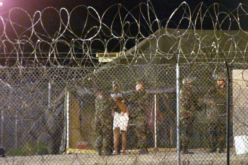 Marines at Camp X-Ray at the Naval Base at Guantanamo Bay, escort a newly arriving detainee into a processing tent after being showered in 2002. Photo: Reuters
