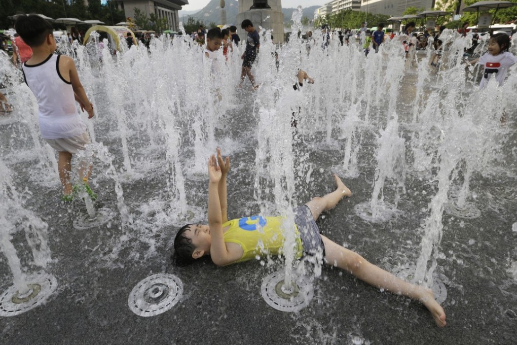A boy cools himself off in a public water fountain in Seoul, South Korea. Photo: AP/Ahn Young-joon