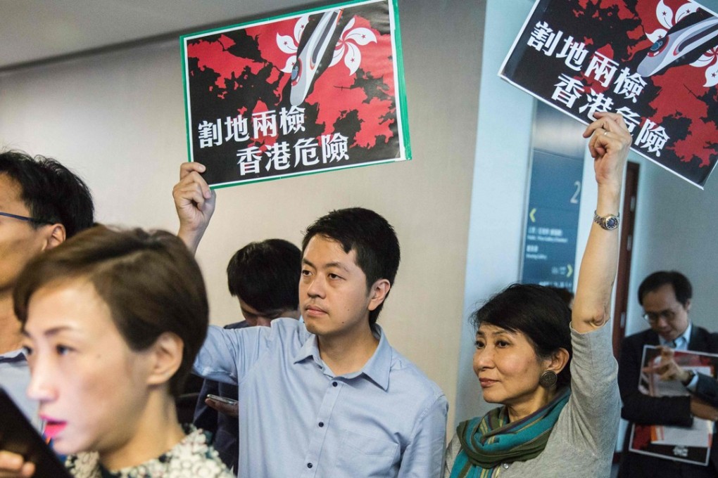 Pro-democracy lawmakers Ted Hui of the Democratic Party and Claudia Mo of the Civic Party hold signs that read “ceding land with co-location puts Hong Kong in danger” as Secretary for Justice Rimsky Yuen (not in picture) speaks at a press conference in Hong Kong, on August 3. Photo: AFP
