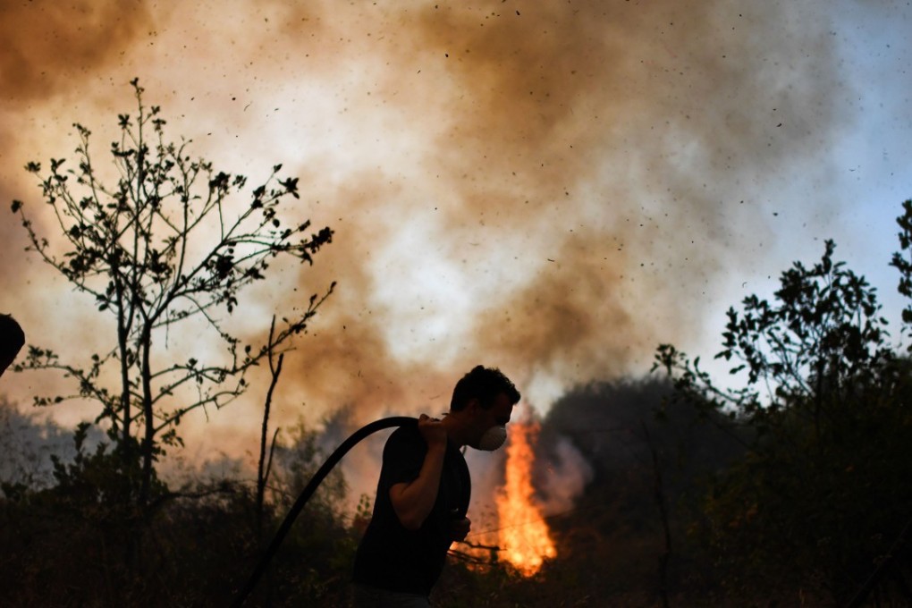 Villagers from Pucarica try to help in extinguishing a wildfire in Abrantes area of Portugal on August 10, 2017. A report said the impact of global warming is getting worse. Photo: AFP