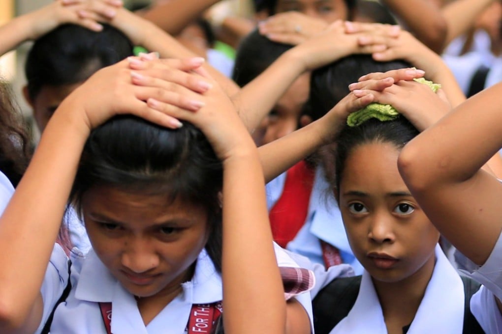 Students use their hands to cover their heads as they evacuate their school premises after an earthquake hit the northern island of Luzon. Photo: Reuters