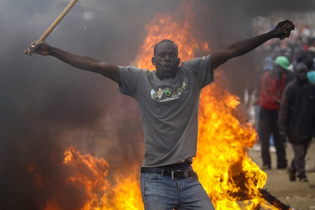 A supporter of Kenyan opposition leader Raila Odinga stands in front of a burning barricade during battles with riot police in Kibera slum, Nairobi. Photo: EPA
